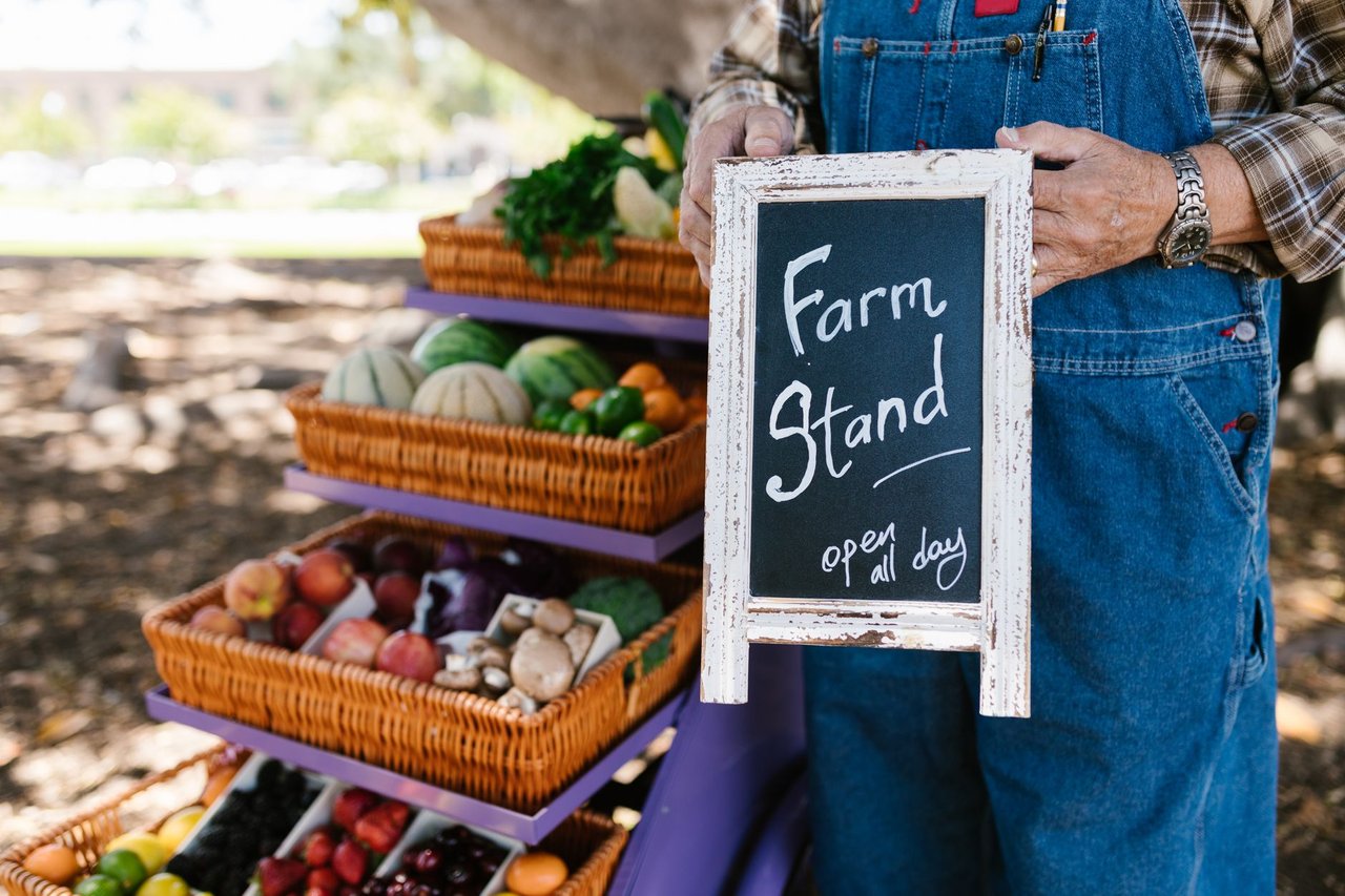 Banca ao ar livre com frutas e verduras frescas organizadas em cestos.