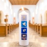 Interior de uma igreja com uma vela junto a uma pia batismal, em referência ao rito cristão do batismo.